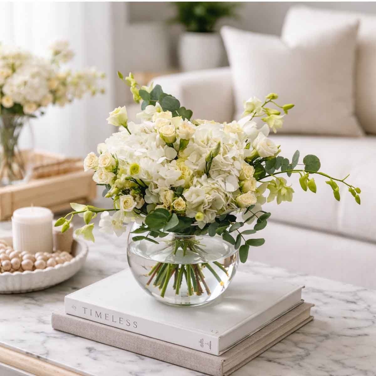 تنسيق النقاء في مزهرية من الزهور الطبيعية – 2 هدرانج بيضاء مع 1 يوستوما بيضاء، 4 أوركيد أبيض صغير، 5 ورود بيضاء صغيرة و2 أوكالبتوس